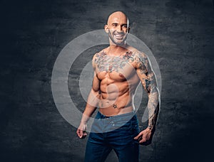 Shaved head, muscular male with tattoos on his torso over grey v