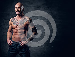 Shaved head, muscular male with tattoos on his torso over grey v