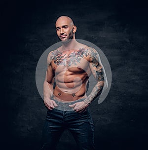 Shaved head, muscular male with tattoos on his torso over grey v