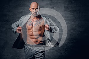 Shaved head tattooed male dressed in a grey jacket on a naked to