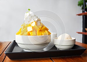 Shaved ice dessert served with mango sliced and whipping cream.