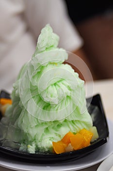 Shaved ice, lemon flavor, decorated with brightly colored fruits in a black plate