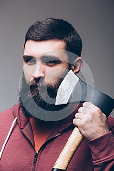 Shaving with axe. Portrait of Confident young bearded man carrying a big axe
