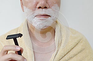 shaving cream on man face with shaver on right hand prepare to shaved