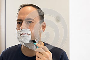 Shaving Man on foam with razor mirror in bathroom