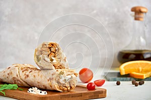 Shawarma with chicken on wooden board, closeup photo