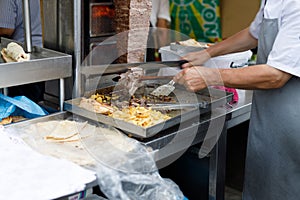 Shawarma seller cuts chicken meat from a spit