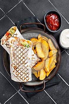 Shawarma Shaurma kebab with meat, vegetable salad and french fries. Black background. Top view