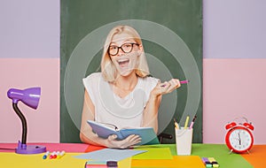 Shcool teacher in class on blackboard background. Professional portrait. Female student taking notes from a book at