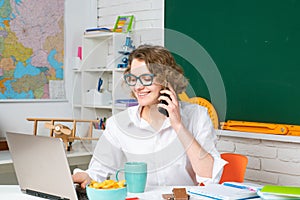 Shcool teacher with mobile phone use laptop in class on blackboard background. Professional portrait.