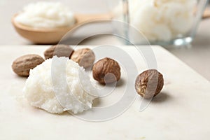 Shea butter and nuts on marble board. Space for text