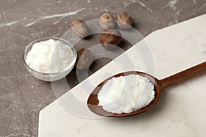 Shea butter in wooden spoon and bowl with nuts