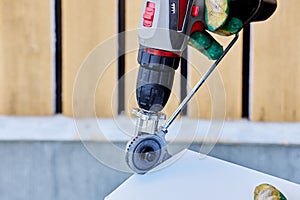 Shears attachment cutter for electric drill, worker cuts sheet metal to finish window opening.