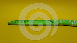 Sheathed green kitchen knife isolated on yellow background.