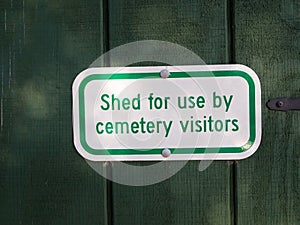 Shed for use by cemetery visitors sign on green wood