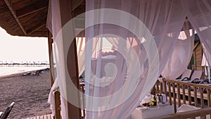 Sheds with fabric white curtains on the beach in the evening.