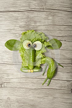 Sheep made with cucumber and salad on wooden background