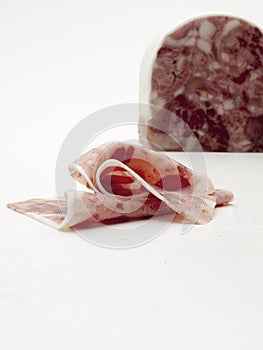 Sheet cut of sausage of wild boar meat on a white table and background. photo