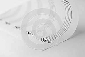 Sheet with empty staves for music notes and treble clef on white background, closeup