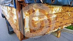 Sheet metal corrosion of old truck body. Rusty surface, background and damaged texture from road salt and reagents. Protection car