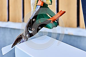 Sheet metal shears snips cut edge of galvanized steel from roofing iron, outdoor work.