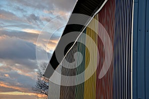 Sheet metal wall of an industrial hall made of corrugated sheet metal in bright colors. Striped sheets complement the interestingl