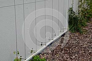 The sheet metal wall of the warehouse is improved with stainless steel cable holders for climbing plants. trellises made of stainl