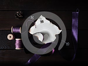 Sheet of old paper with purple ribbons and thread on a wooden table. top view