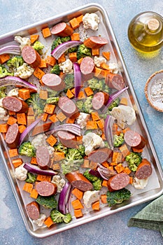 Sheet pan dinner with sausage and vegetables ready to be roasted