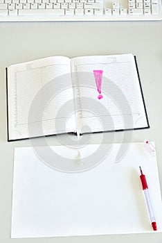 Sheet of paper, diary and red pen on a desk - vertical