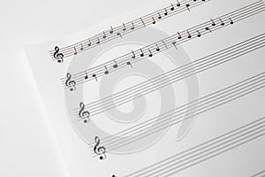 Sheet of paper with music notes on white background, closeup view