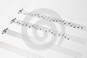 Sheet of paper with music notes on white background, closeup view