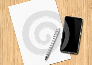 Sheet of paper with pen and smartphone on a wooden desk