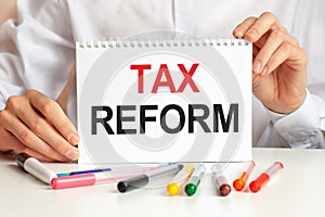 A sheet of paper with text tax reform, multicolored markers on a white table. Business and educational concept