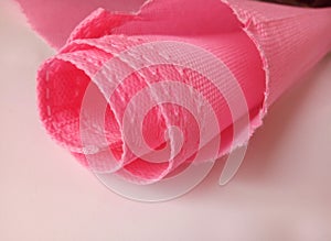 A sheet of pink polypropylene fabric with rough cut edges
