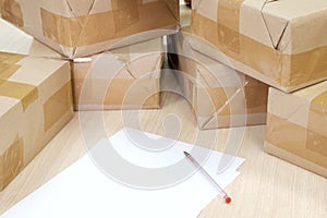 A sheet of white paper and a fountain pen on a background of sealed shipping boxes