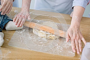 Sheeting dough. Women`s hands are holding rolling pin and floured. Hands baking dough with rolling pin. Baking in