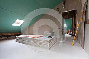 Sheets of drywall, parts of scaffolding, handle tools and construction material in the room of apartment during on the remodeling