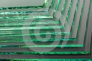 Sheets of Factory manufacturing tempered clear float glass panels cut to size. Dark background