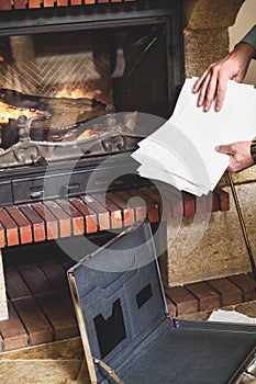 Sheets of paper in hands of man and fireplace