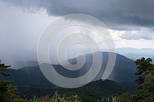 Sheets of rain falling thickly on a mountain vista obscuring parts of the distance, rainy weather event from a cloudburst