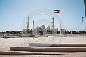 Sheikh Zayed Grand Mosque in Abu Dhabi with large UAE flag in United Arab Emirates on a sunny day