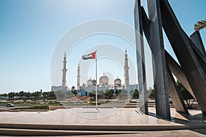 Sheikh Zayed Grand Mosque in Abu Dhabi with large UAE flag in United Arab Emirates on a sunny day