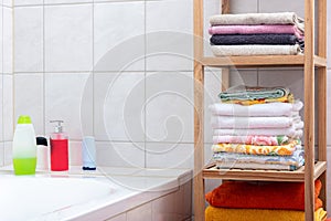 Shelf with colorful towels in the bathroom and hygiene products in the background