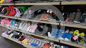 The shelf with footwear for boys, girls and children in the store. Kids shoes, sneakers and various colored boots in