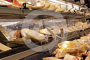 Shelf in the grocery store with large selection of various Italian cheese delicacies in different packages, shapes, types,