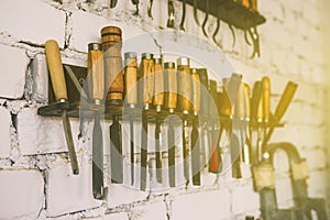 Shelf with hand tools on a brick wall background. Chisels, saws and knives for woodworking. Carpentry workshop.