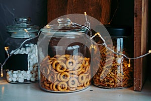 shelf with snacks in the kitchen. Grocery shelf in glass jars. Shelf with dryers and marshmallows with a Christmas garland.