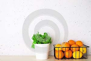 Shelf in a white kitchen with fresh fruits, herbs, cutlery, kitchen utensils, tools, textiles, fresh water in a decanter