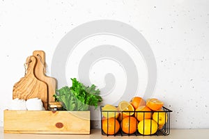 Shelf in a white kitchen with fresh fruits, herbs, cutlery, kitchen utensils, tools, textiles, fresh water in a decanter